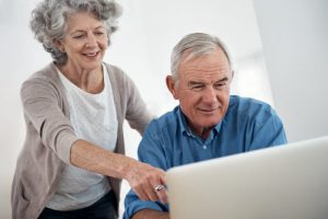 Een vrouw geeft hulp aan een oudere man met zijn bankzaken bij inloopspreekuren in de bibliotheek.