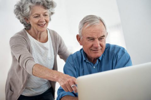 Een vrouw geeft hulp aan een oudere man met zijn bankzaken bij inloopspreekuren in de bibliotheek.