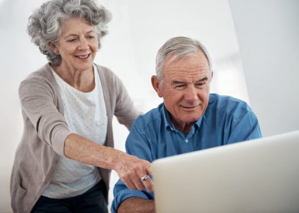 Een vrouw geeft hulp aan een oudere man met zijn bankzaken bij inloopspreekuren in de bibliotheek.