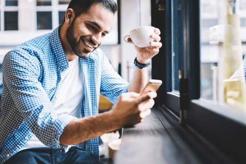 Man met koffie en mobiel met bankapp