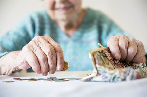 Bejaarde vrouw telt contant geld uit haar portemonnee.