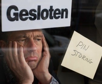 Een teleurgestelde ondernemer die een pinstoring ervaart. De winkel is helaas gesloten.