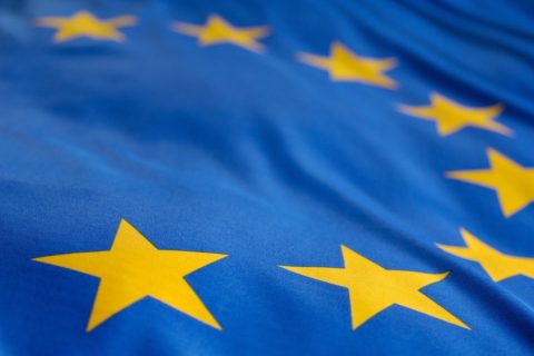 Close-up van de Europese Unie-vlag met gouden sterren op een blauwe achtergrond.